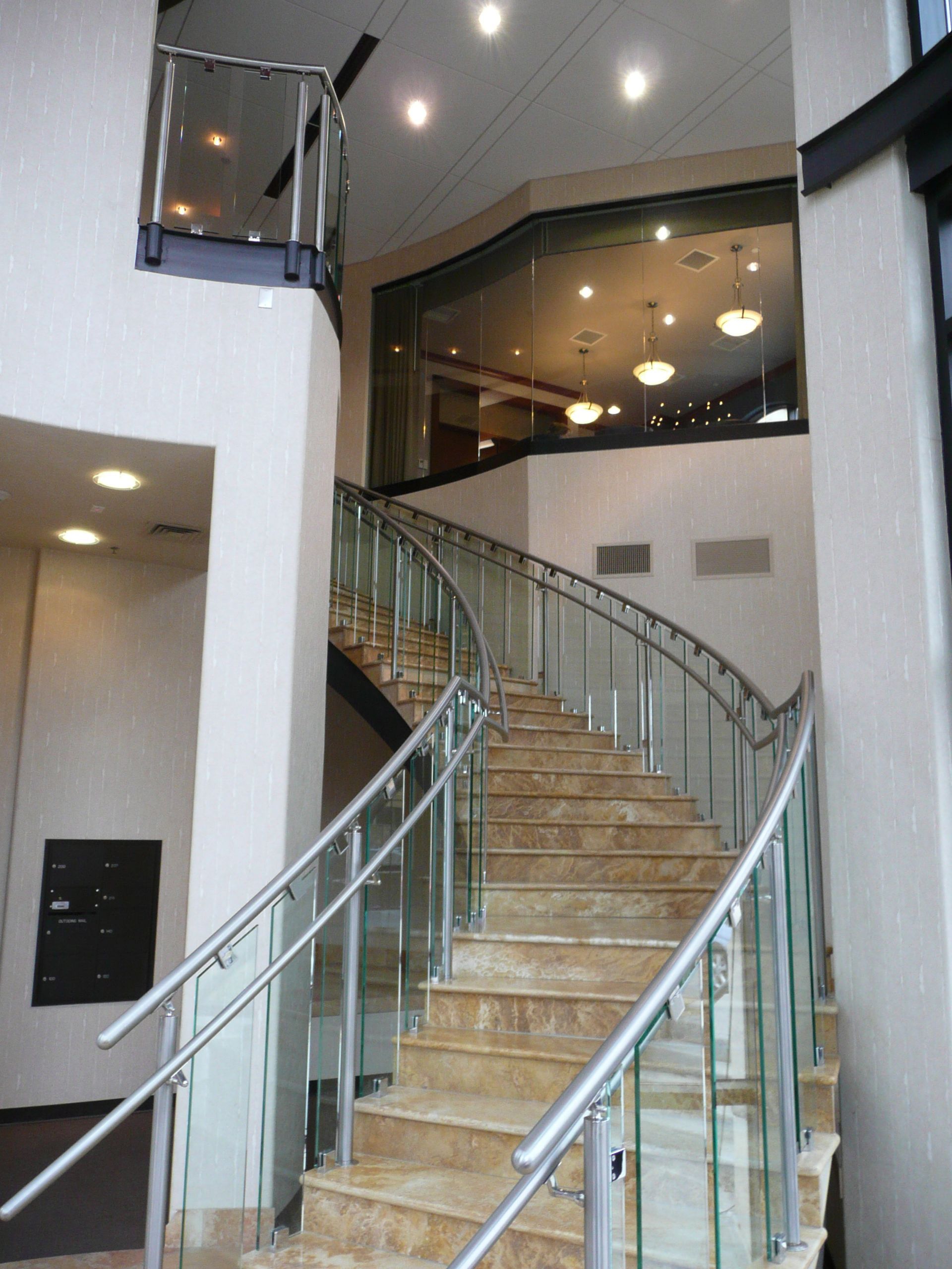 Curved staircase with glass and metal railings in a modern indoor lobby