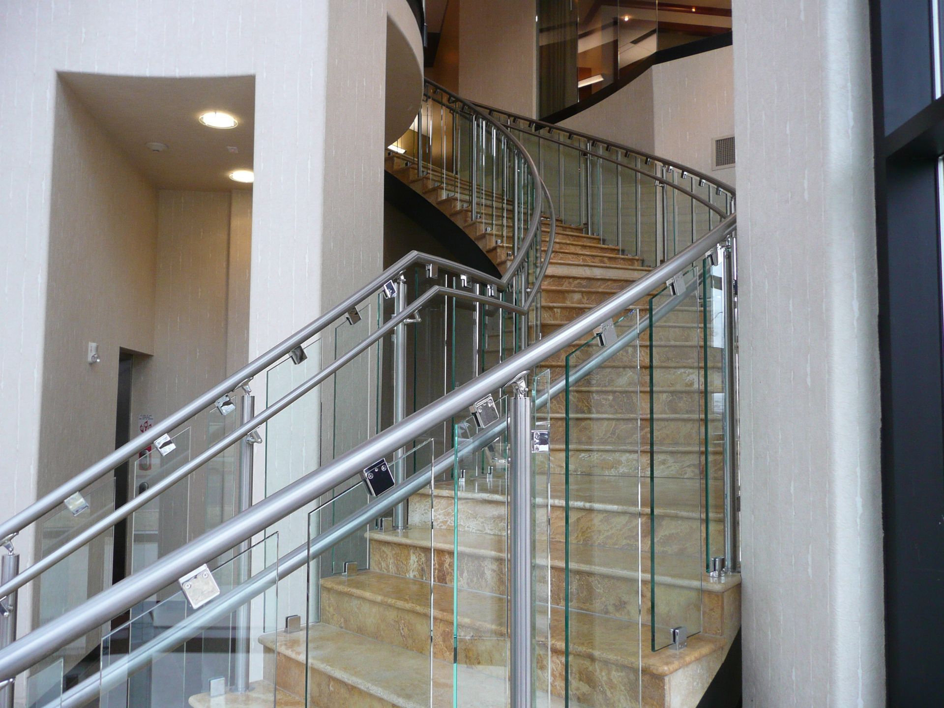 Indoor staircase with glass railings and beige walls in a modern building lobby