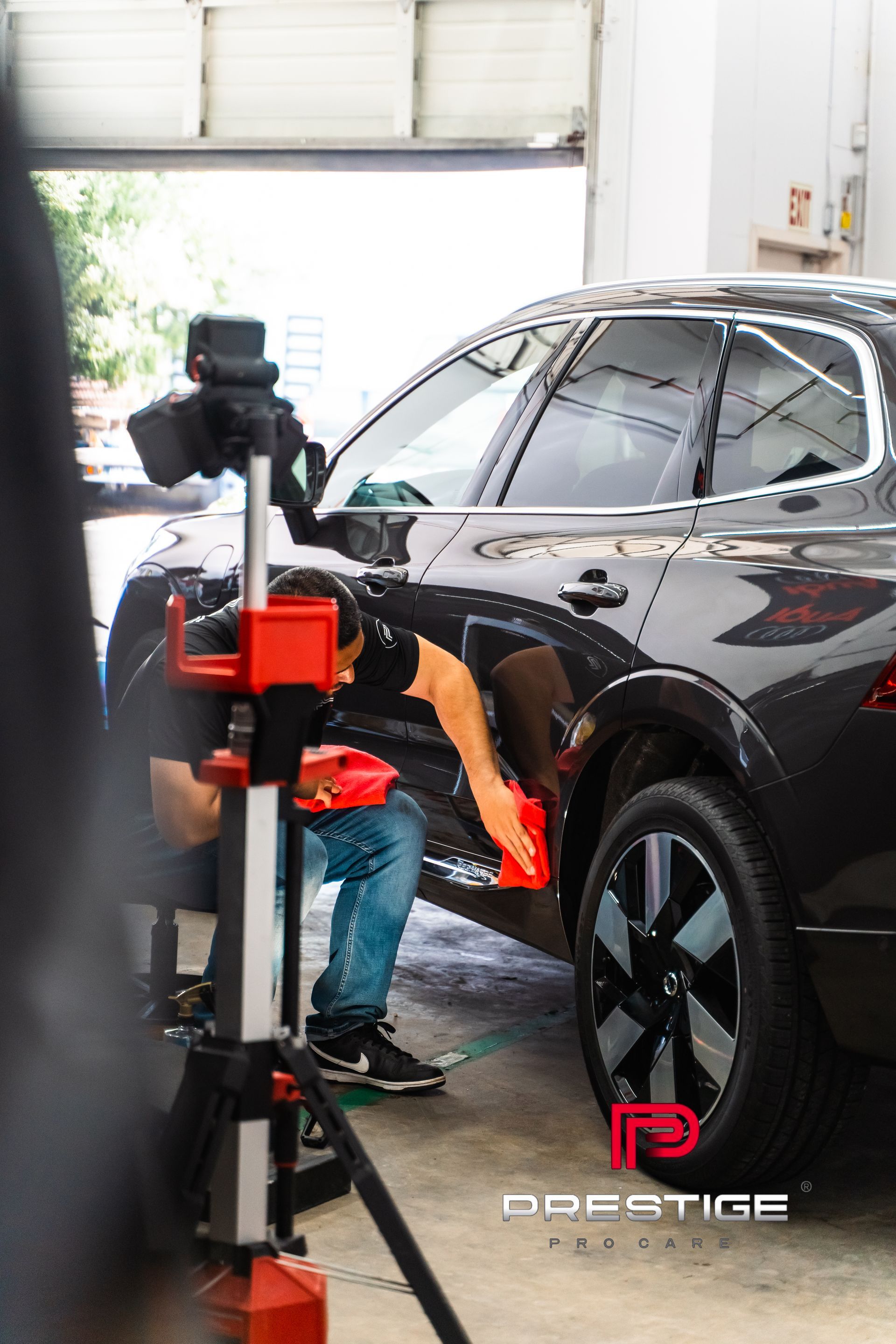 A man is polishing a car in a garage.
