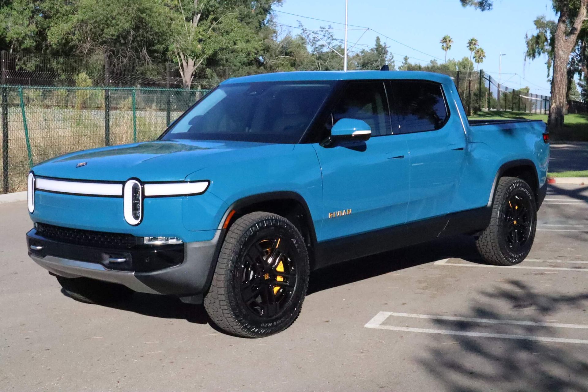 Dark blue truck with tinted window, door open in a workshop. Person’s hand on the door frame.