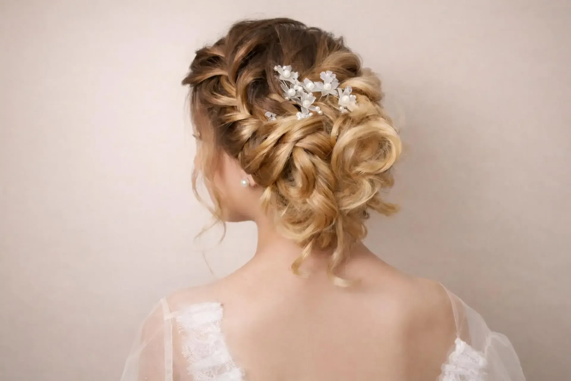 Capelli biondi raccolti da una donna con fermaglio decorativo. Indossa un abito bianco in pizzo.