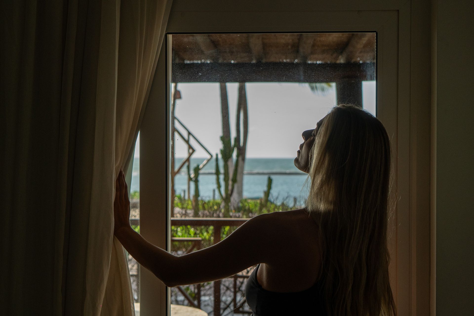 Mulher abrindo a cortina do nosso quarto frente mar revelando a vista do mar Praia do Francês.