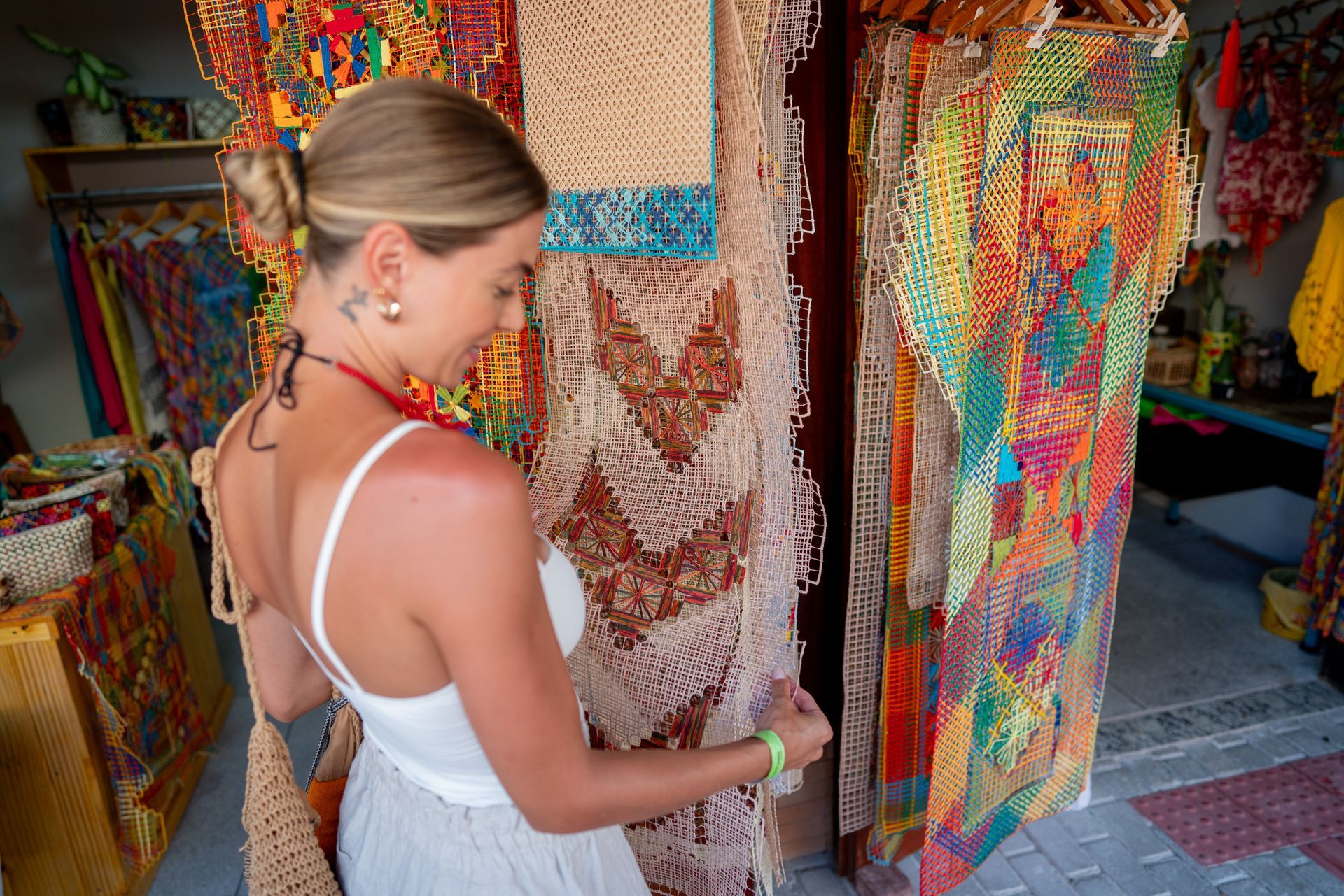 Mulher admirando obras de Filé expostas na Vila do Artesanato, na Praia do Francês.