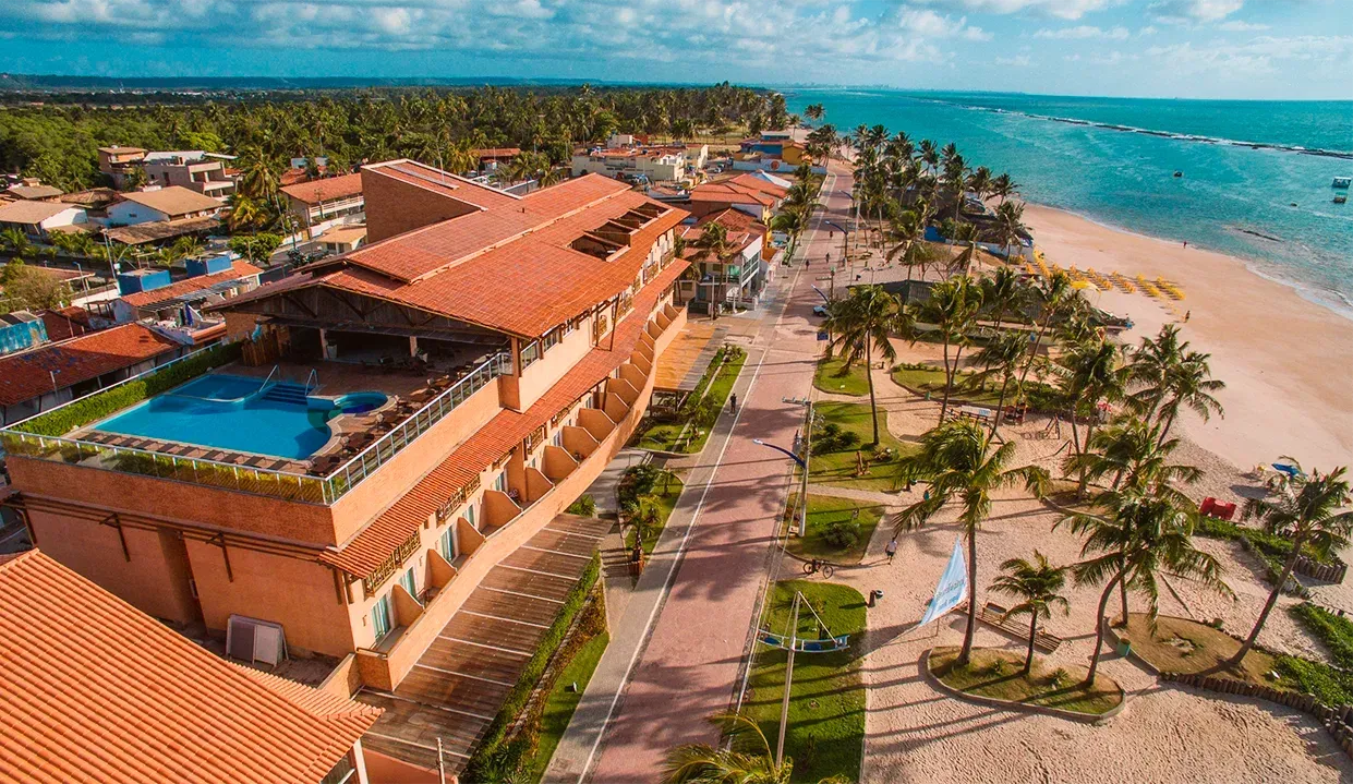 Uma vista aérea de um resort de praia com piscina e palmeiras.