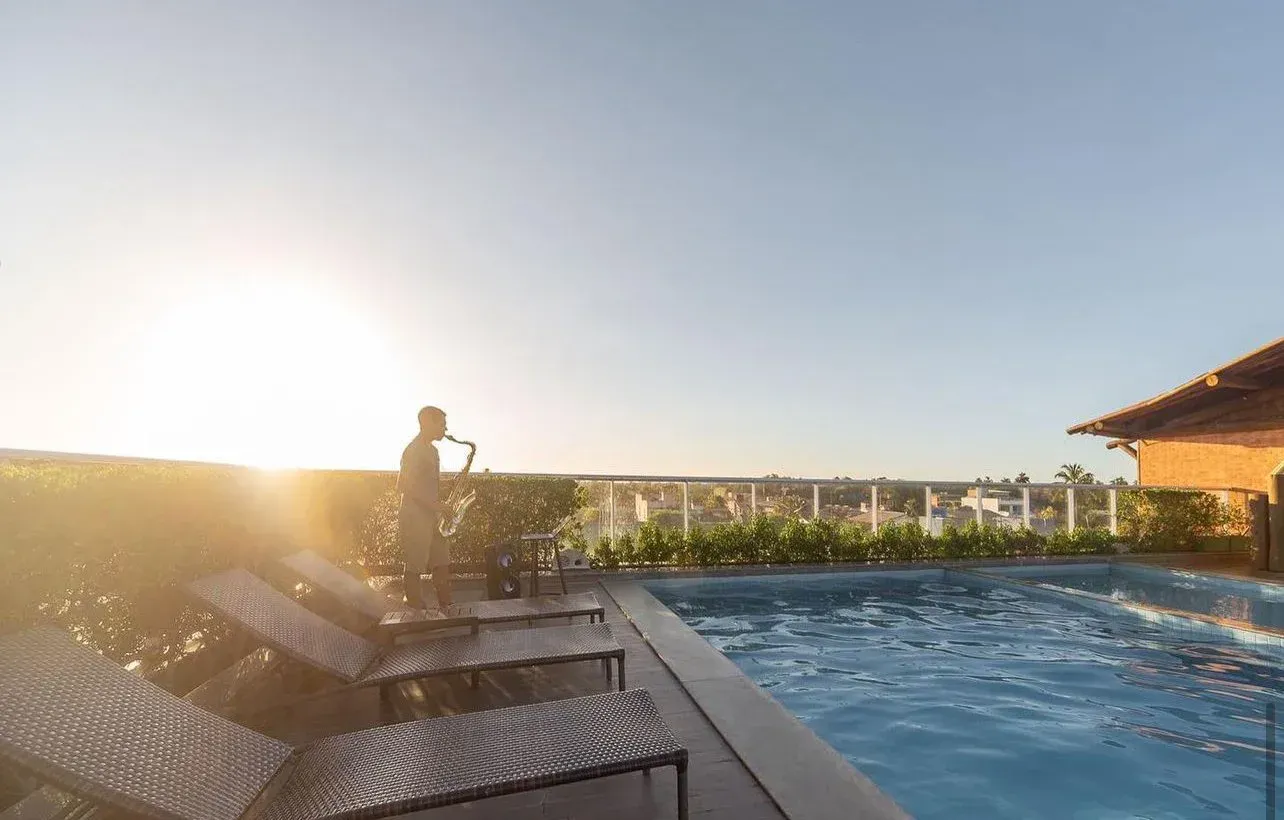 Foto de homem tocando saxofone no por do sol no rooftop do Hotel Ponta Verde Praia do Francês
