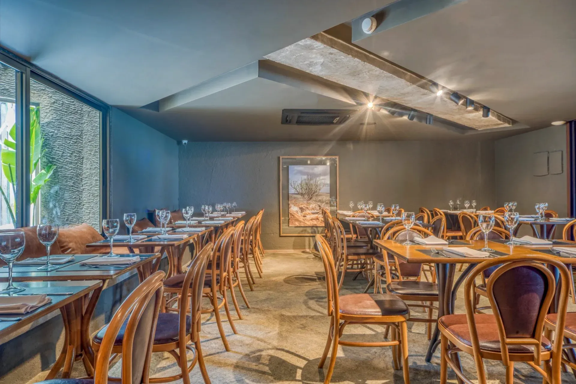 Um restaurante cheio de mesas e cadeiras e uma grande janela.