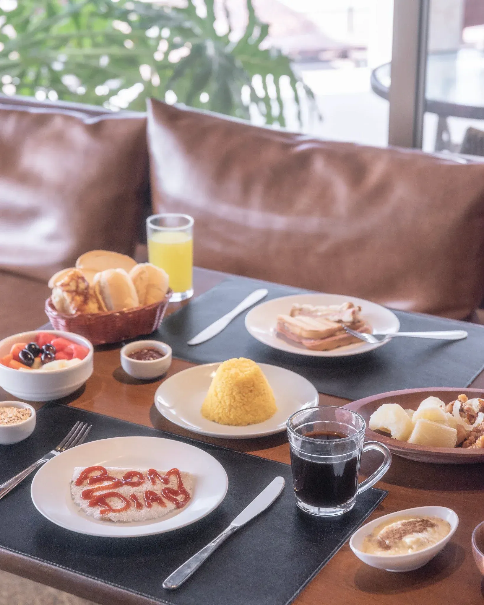 Uma mesa coberta com pratos de comida e um copo de suco de laranja.
