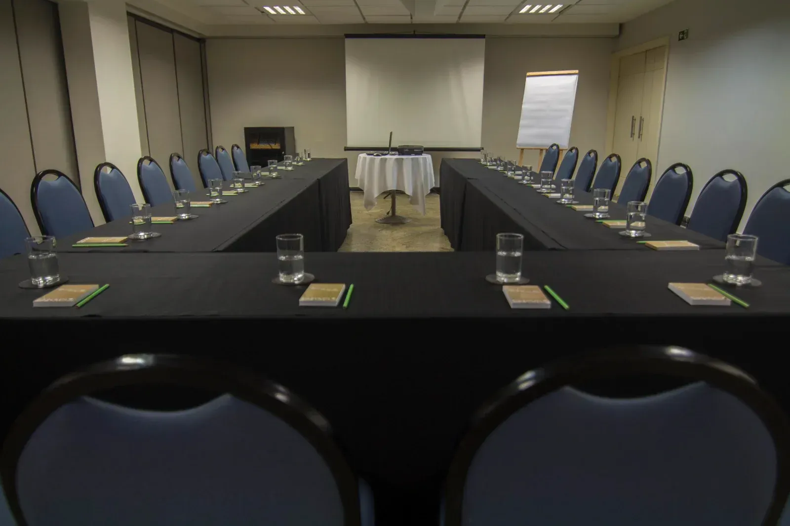 Uma sala de conferências com mesas e cadeiras e uma tela de projetor