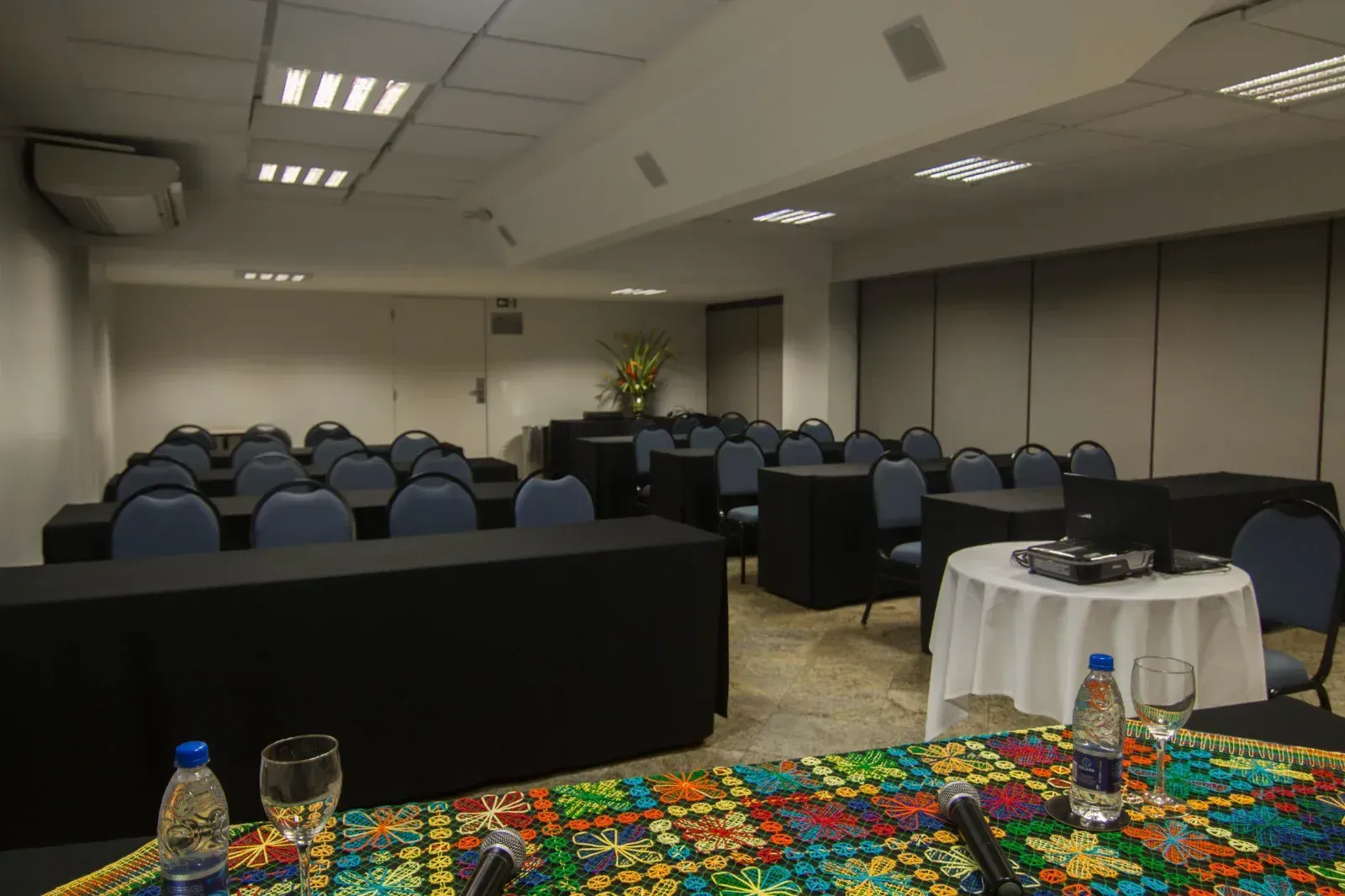 Uma sala de conferências com mesas e cadeiras e uma mesa com um microfone