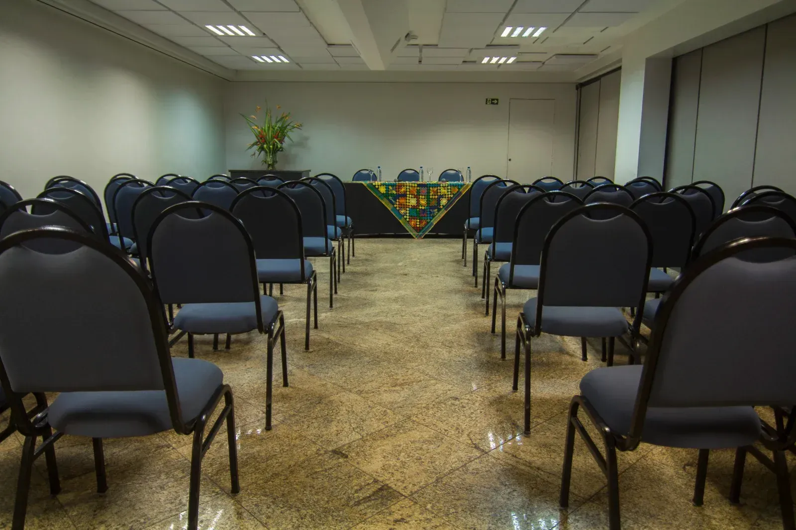 Uma sala de conferências com fileiras de cadeiras e uma mesa.