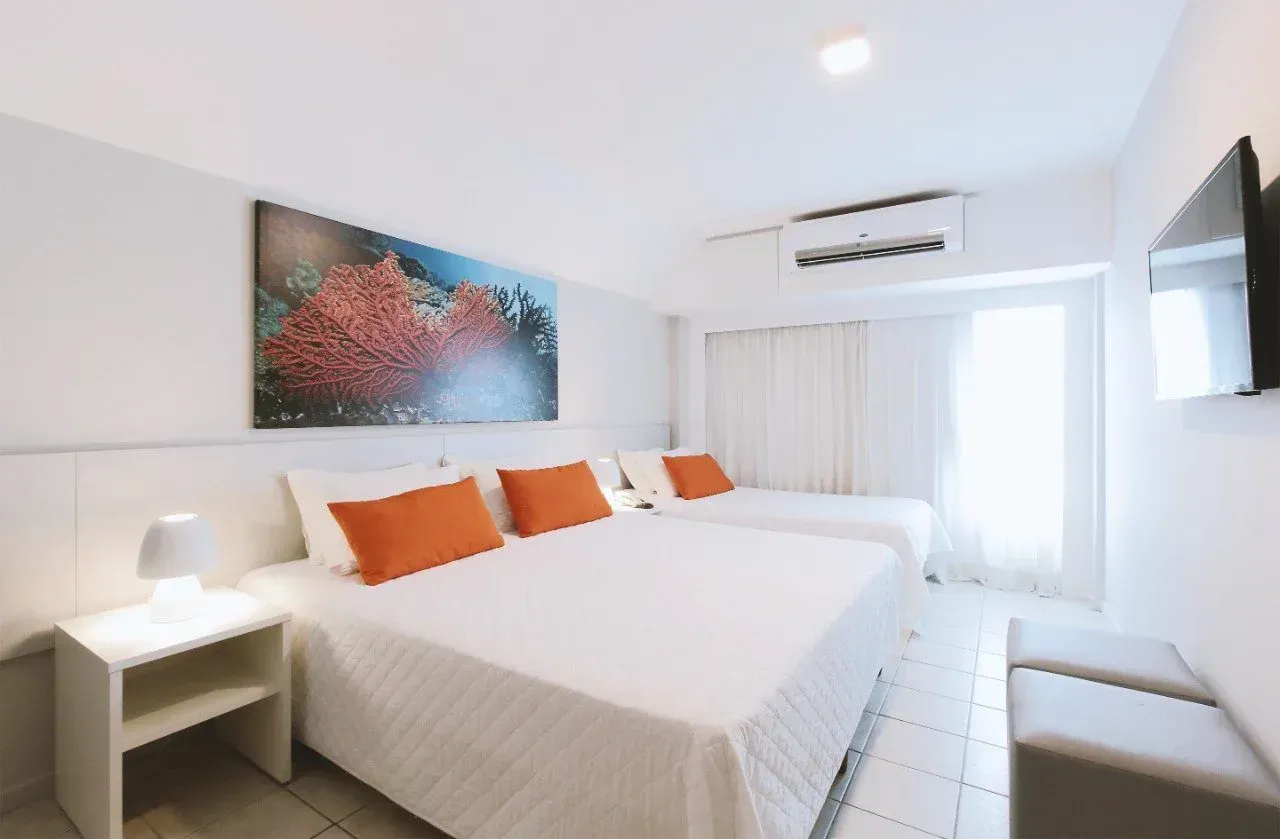 Um quarto de hotel com uma cama grande e duas camas menores.