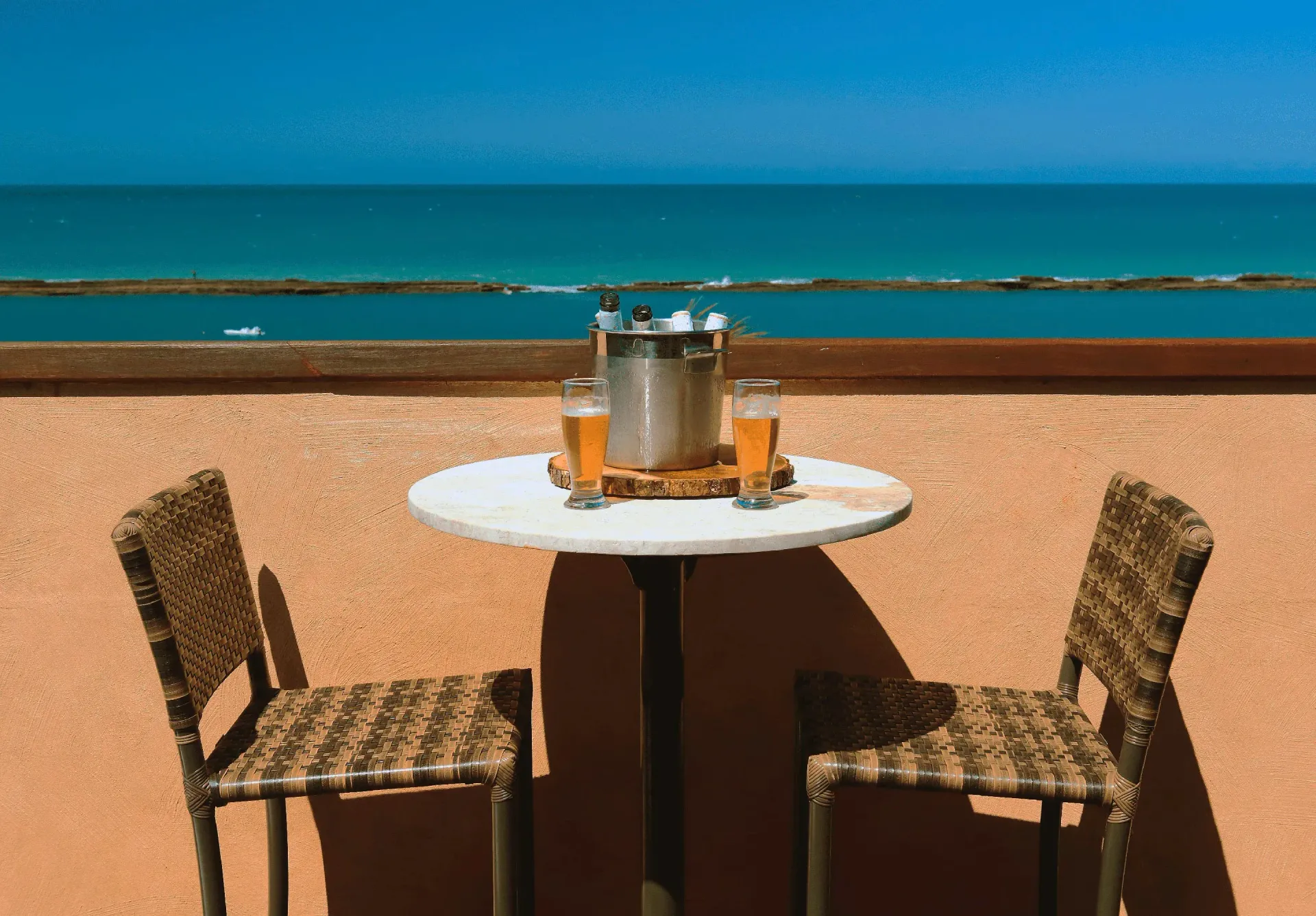 Uma mesa com duas cadeiras e um balde de champanhe com vista para o oceano