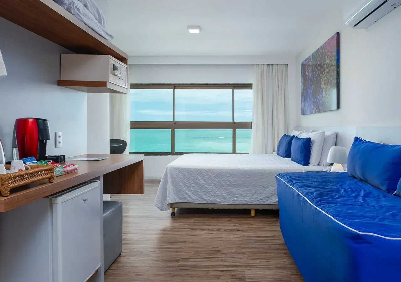 Um quarto de hotel com uma cama grande e um sofá azul.