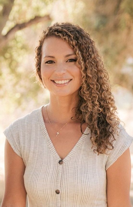 this is sally curran a mental health therapist. She is smiling and has curly hair. 