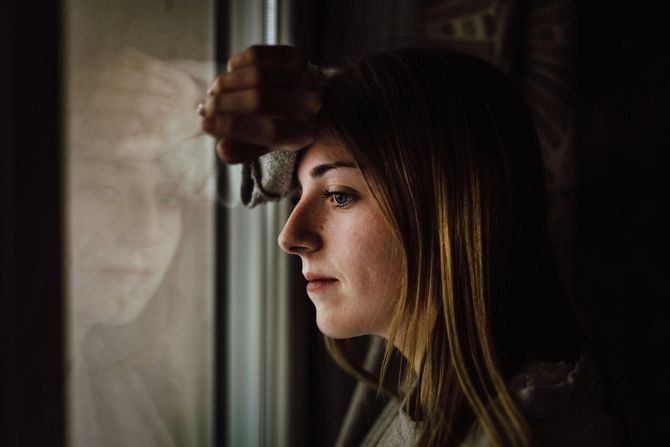 a women looking at the window. She appears to be in deep thought.