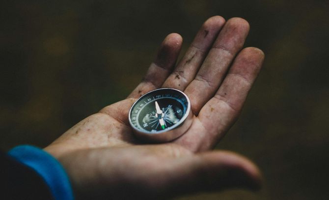 a hand holding a compass, trying to decide which way to go. image to describe life transitions. 