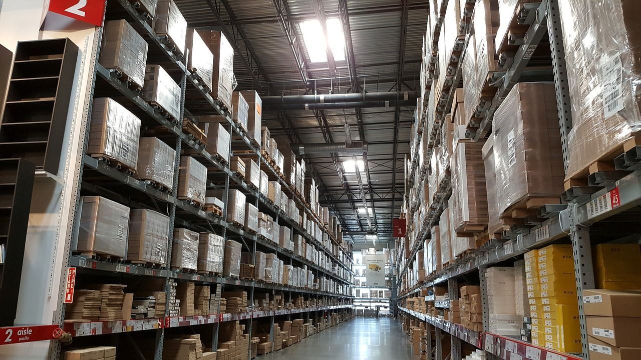 Rows of shelves filled with boxes in a warehouse, with a bright light from above.