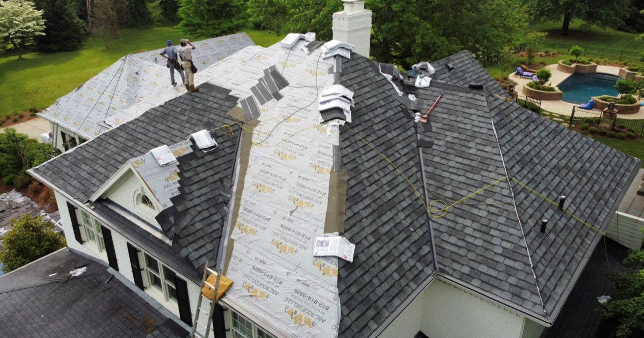 Far aerial view of workers working on roof of large mansion — Georgetown, IN — ARC Roofing LLC
