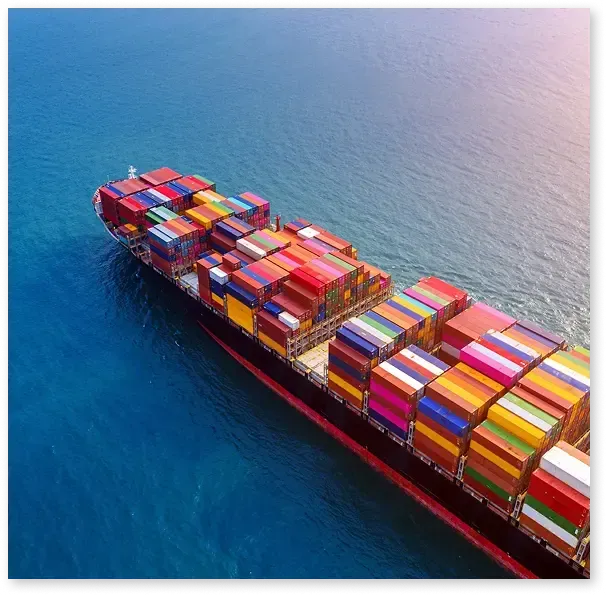 Auto transport carrier loading luxury SUVs at the port terminal with shipping cranes in the background for mainland delivery