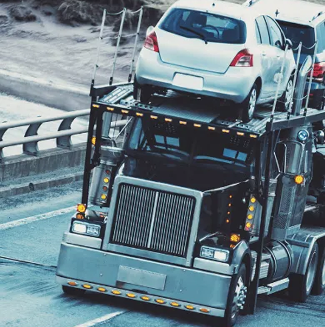 A car carrier truck is transporting several cars on a highway.