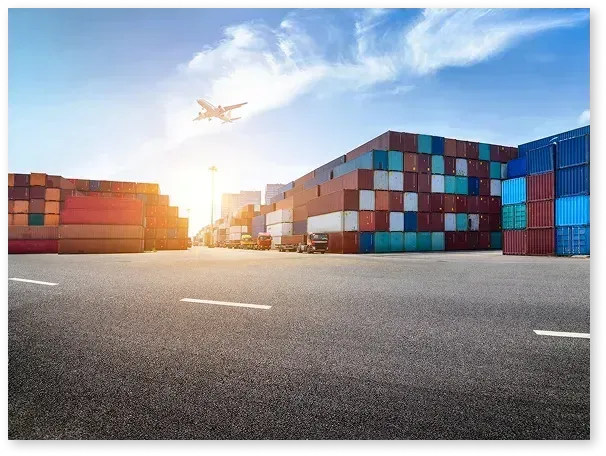 Auto transport carrier loading luxury SUVs at the port terminal with shipping cranes in the background for mainland delivery