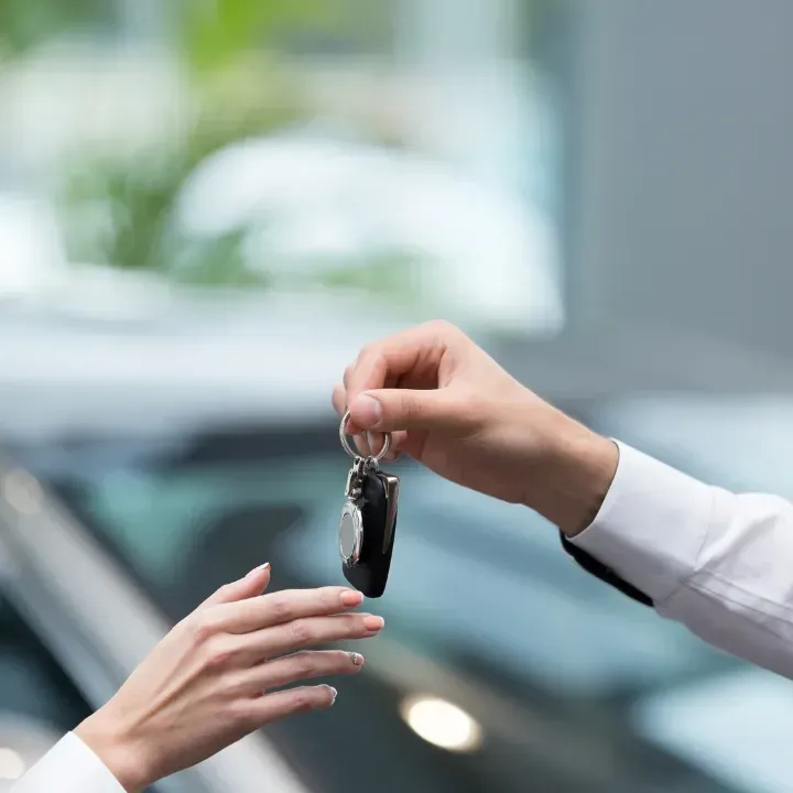 Person handing car keys to another person.