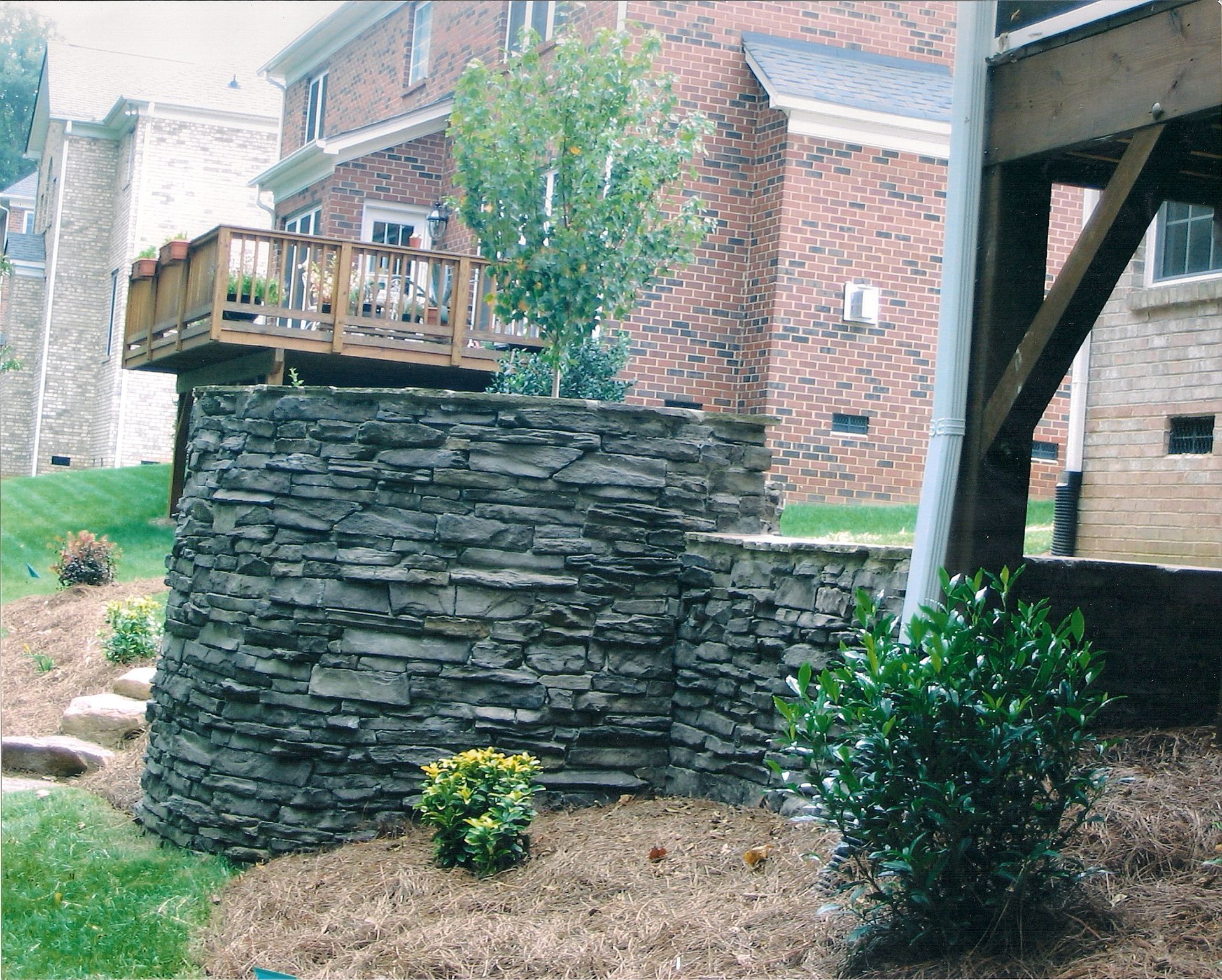 A stone wall with a wooden deck in the background