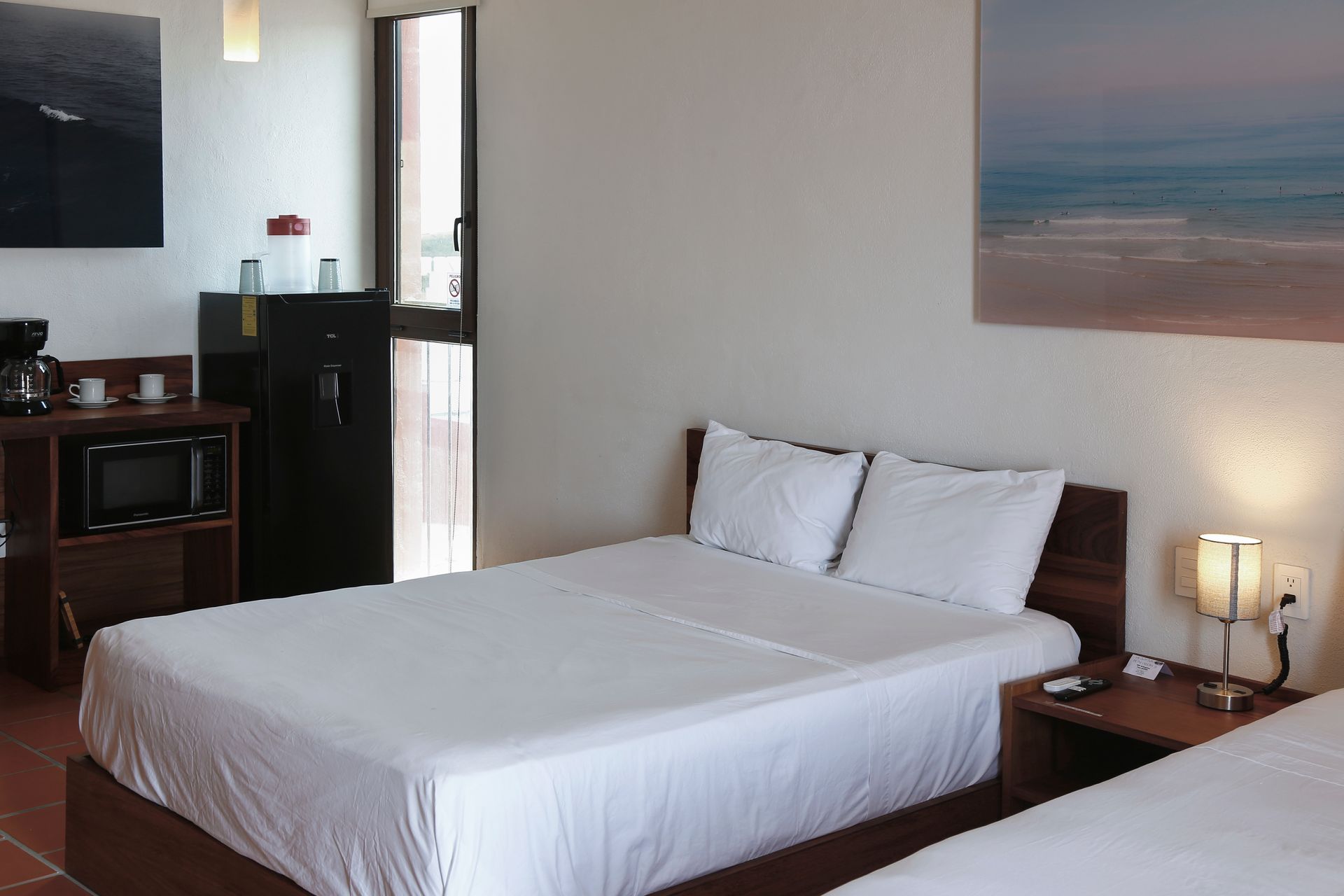 A hotel room with two beds and a painting on the wall