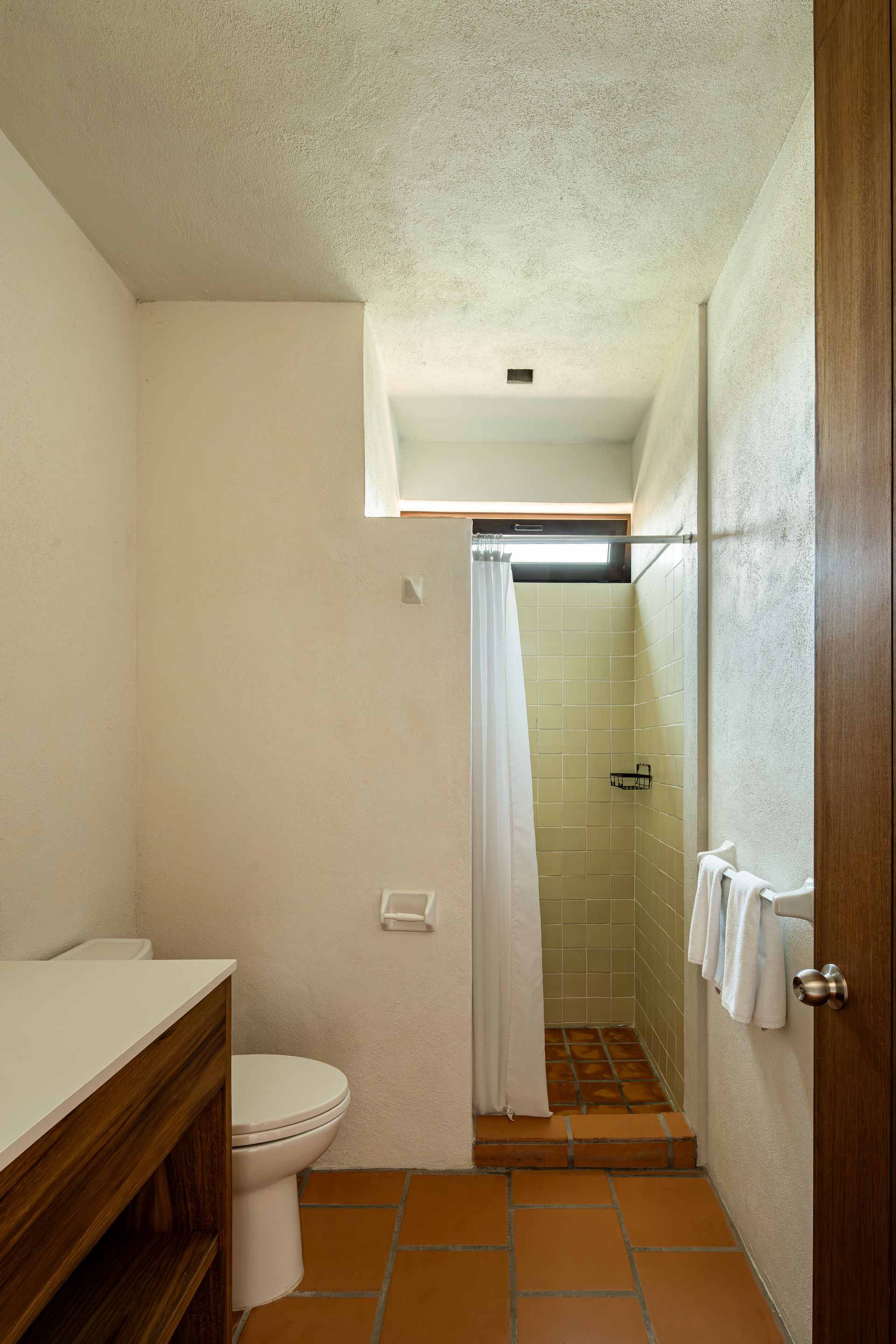 A bathroom with a toilet , sink and shower.