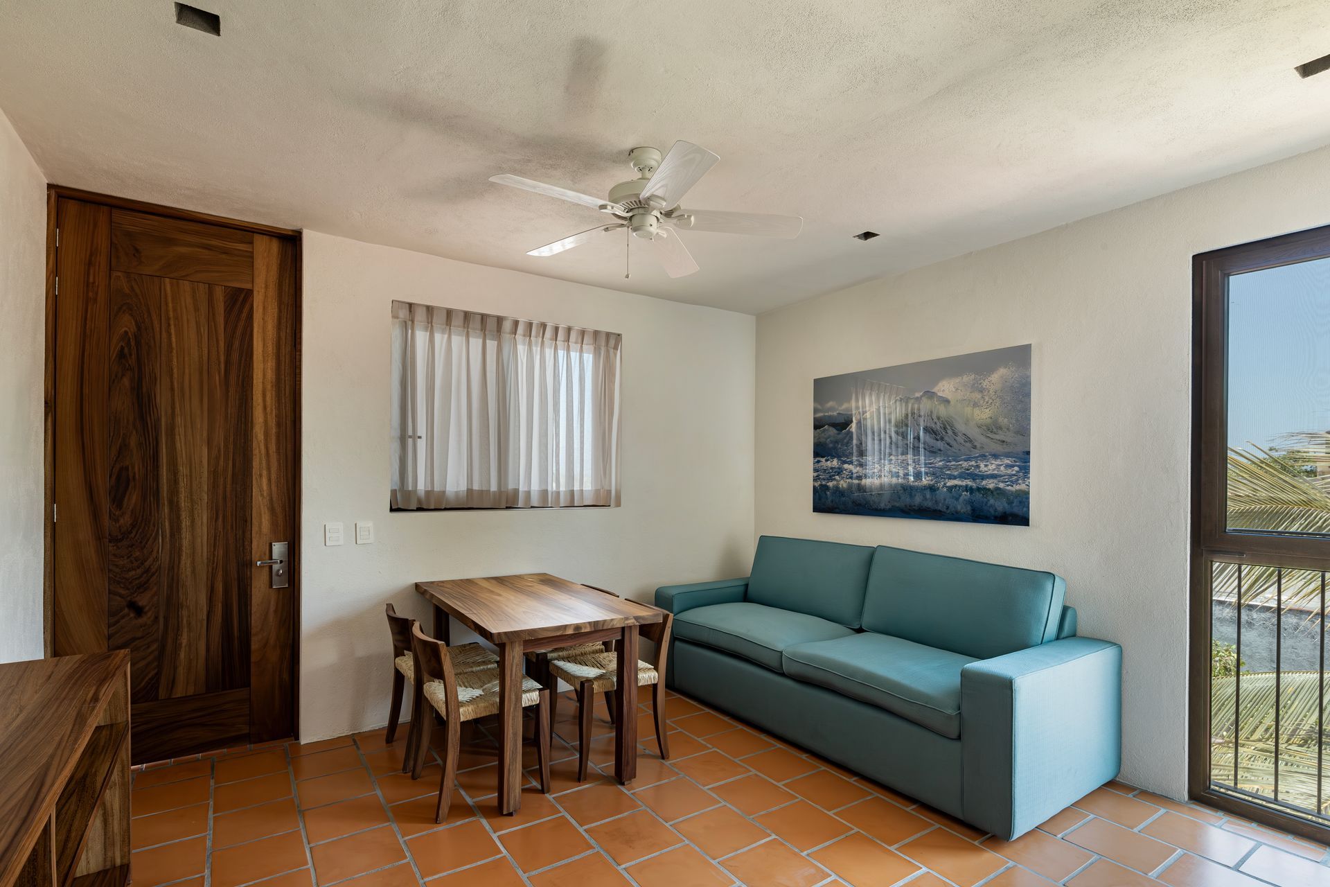 A living room with a couch , table and chairs and a ceiling fan.
