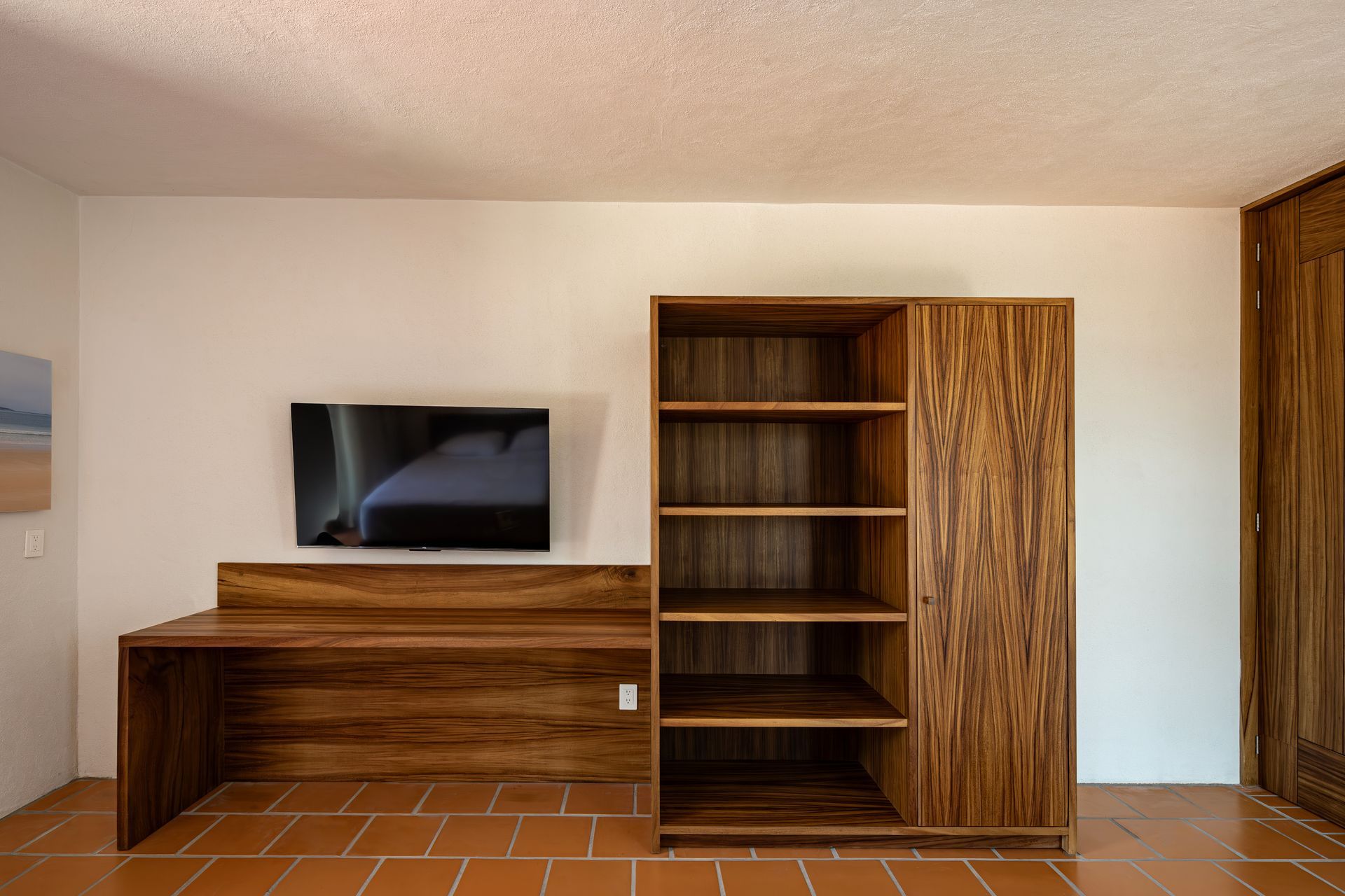 A bedroom with a desk , shelves , and a flat screen tv.