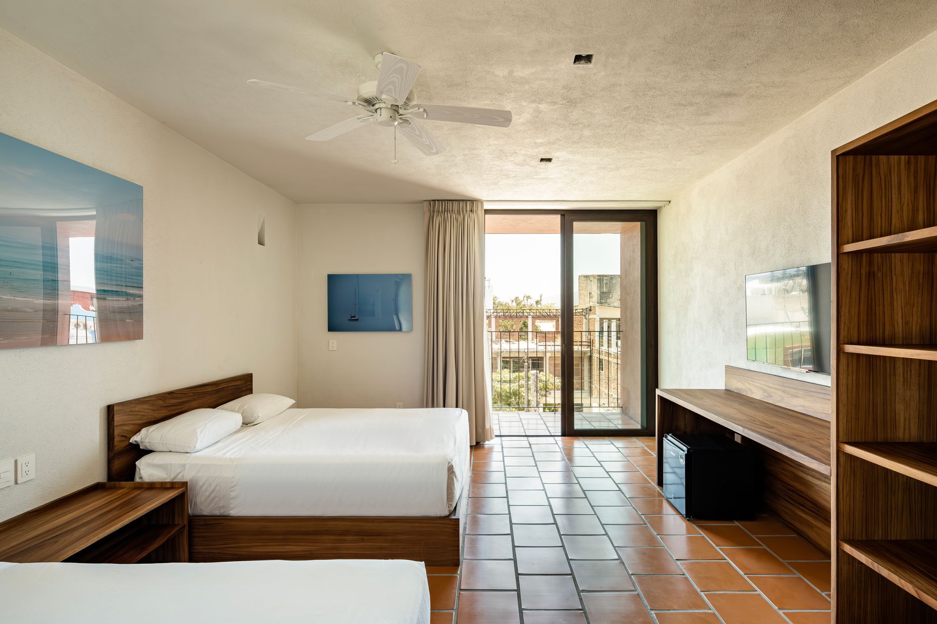 A hotel room with two beds and a ceiling fan.