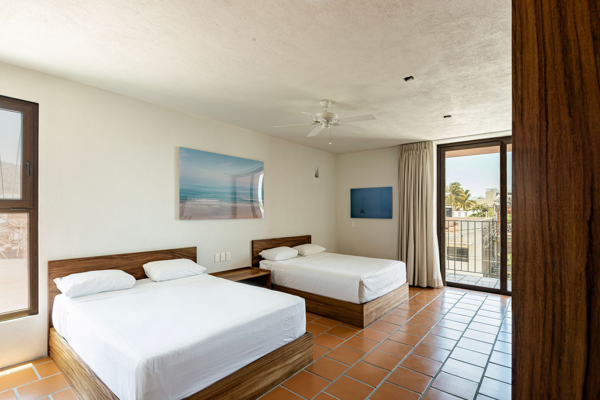A hotel room with two beds and a balcony.