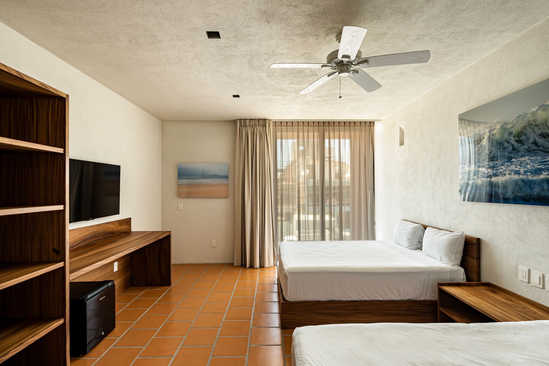 A hotel room with two beds and a ceiling fan.