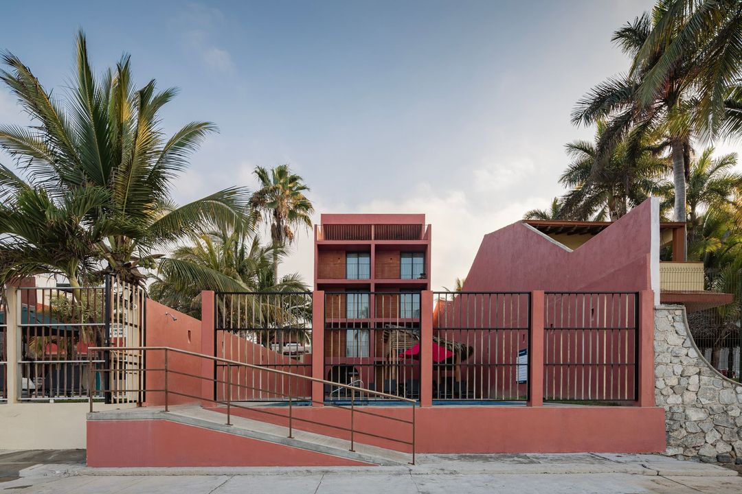 A red building with a ramp and palm trees in the background