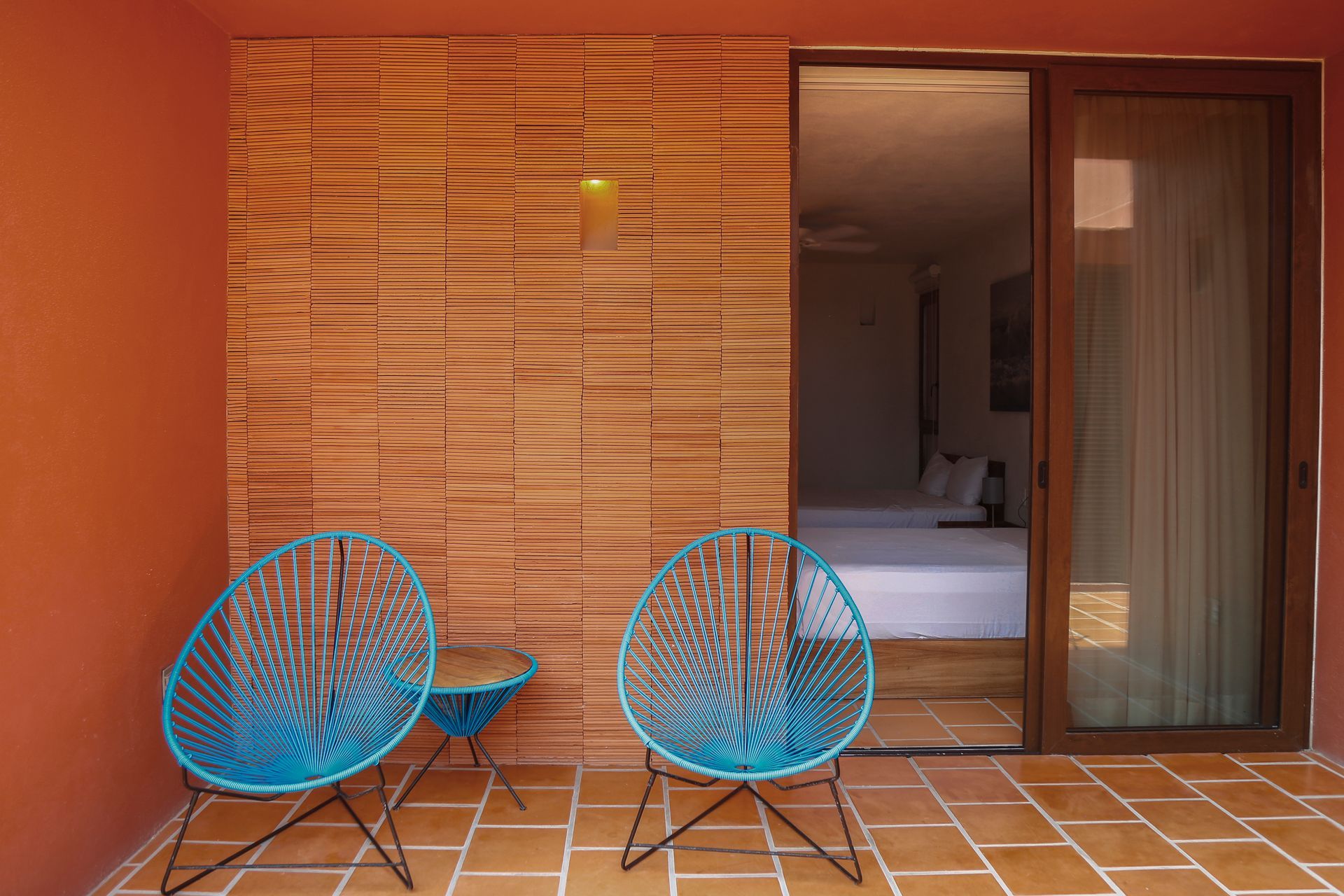 Two blue chairs are sitting on a patio next to a sliding glass door.