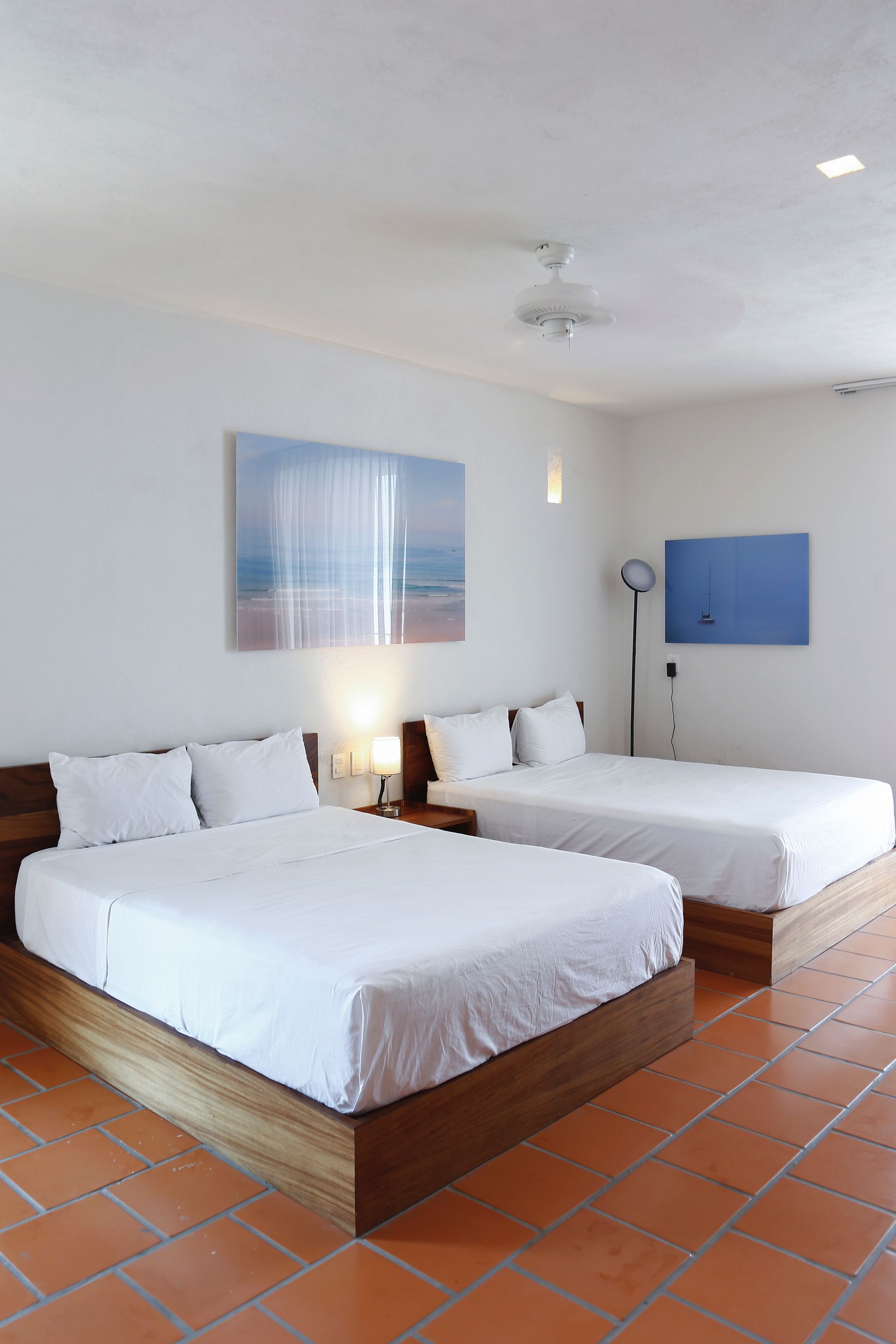 A hotel room with two beds and a painting on the wall.