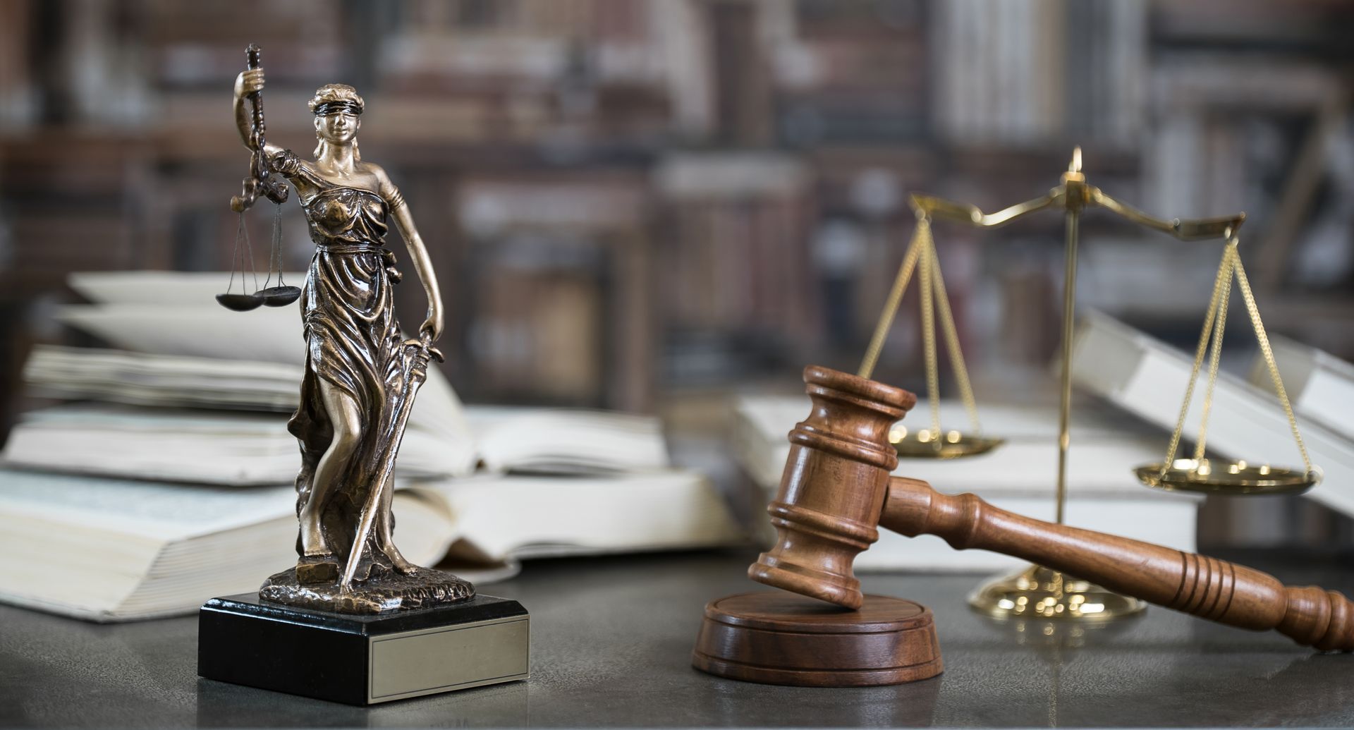 A statue of justice is sitting on a table next to a wooden gavel and scales of justice.