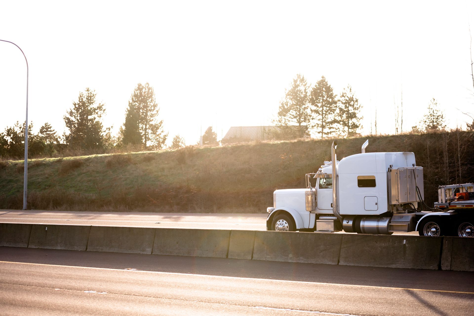 A white semi truck is driving down a highway.