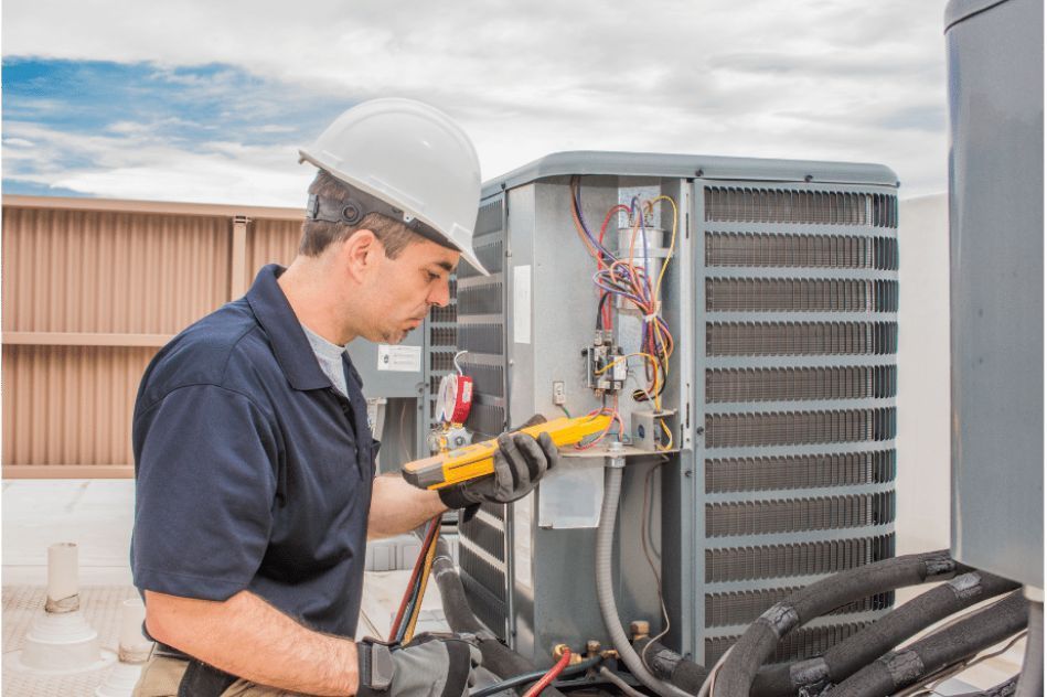 A man wearing a hard hat and gloves is working on an air conditioner.