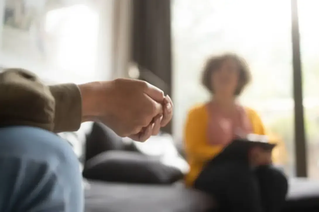 Therapy session highlighting the importance of mental health support and employee rights under Colorado law. Person attending a therapy session, sitting across from a mental health professional in a calm, natural light setting