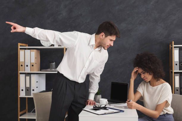 Manager pointing toward the door while scolding an employee, illustrating workplace retaliation.