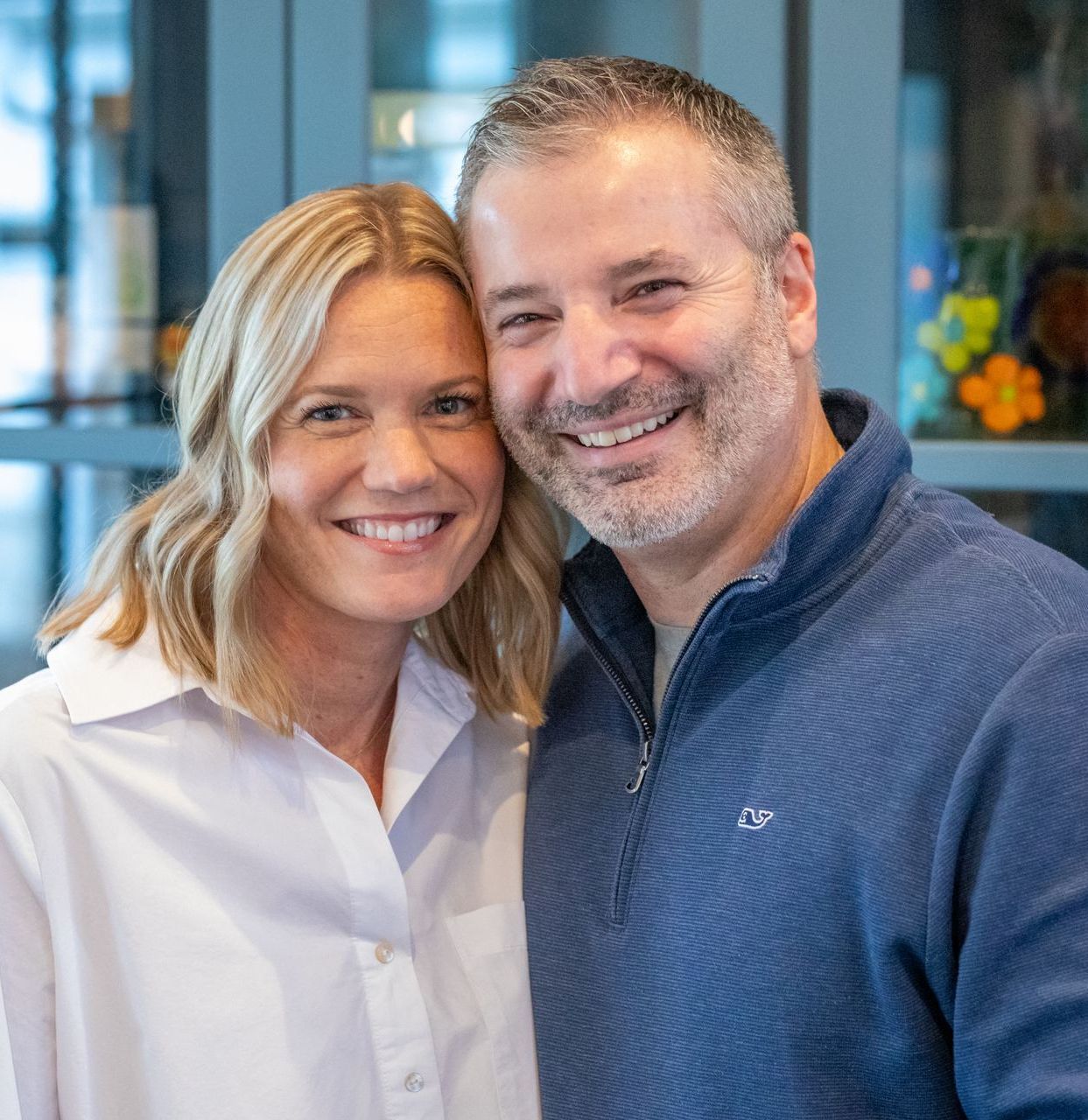 Smiling man and woman; woman with blonde hair, man with gray hair, both close.