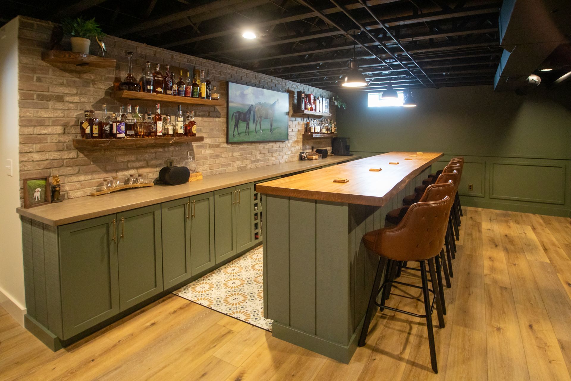 Elegant dark-paneled room with wood floors, recessed ceiling, ornate walls and archway leading to a bar.