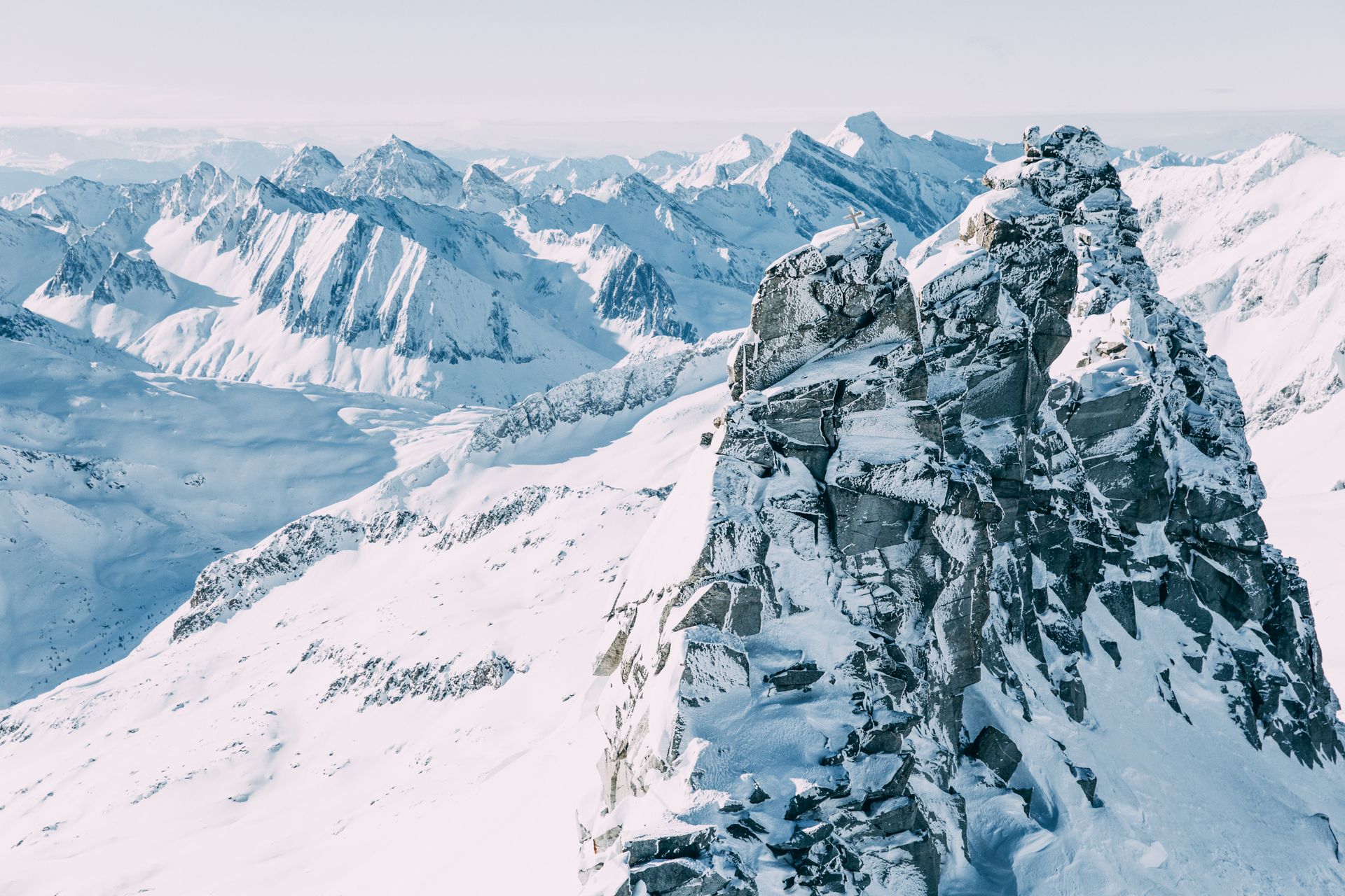 Snowy mountain peaks in a bright, sunny landscape. Focus on the rocky, snow-covered foreground peak.