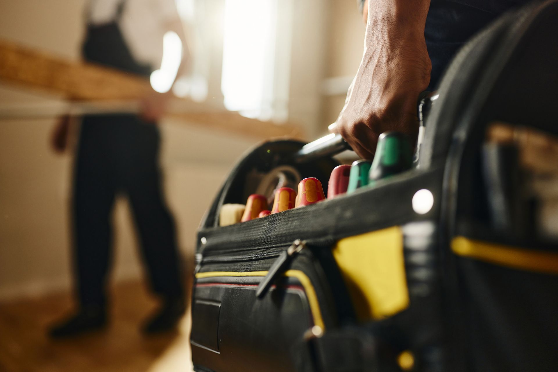 A man is holding a toolbox full of tools.