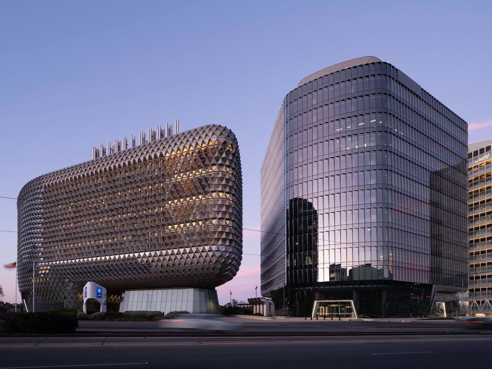 A large building with a lot of windows is next to a smaller building