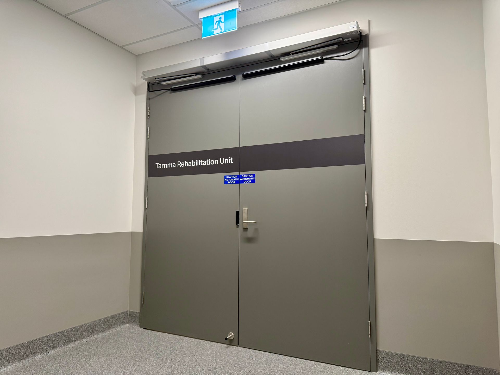 Two wooden doors with black trim are in a hallway