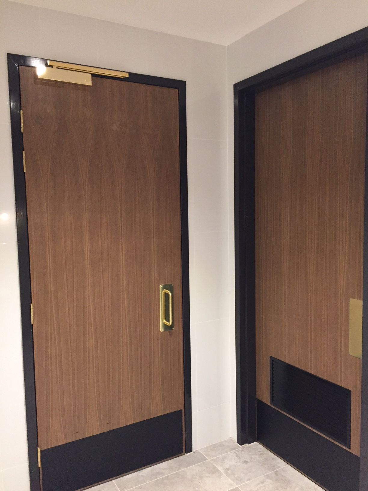 Two wooden doors with black trim are in a hallway