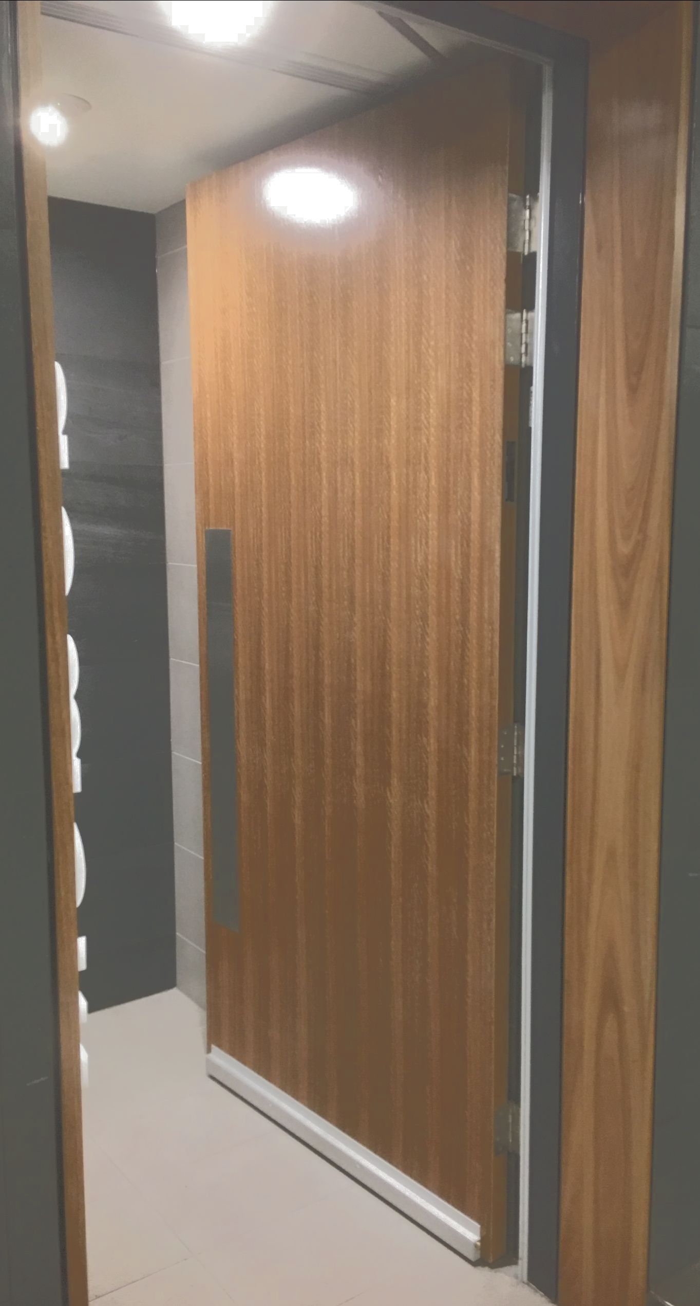 A wooden door is open in a hallway.